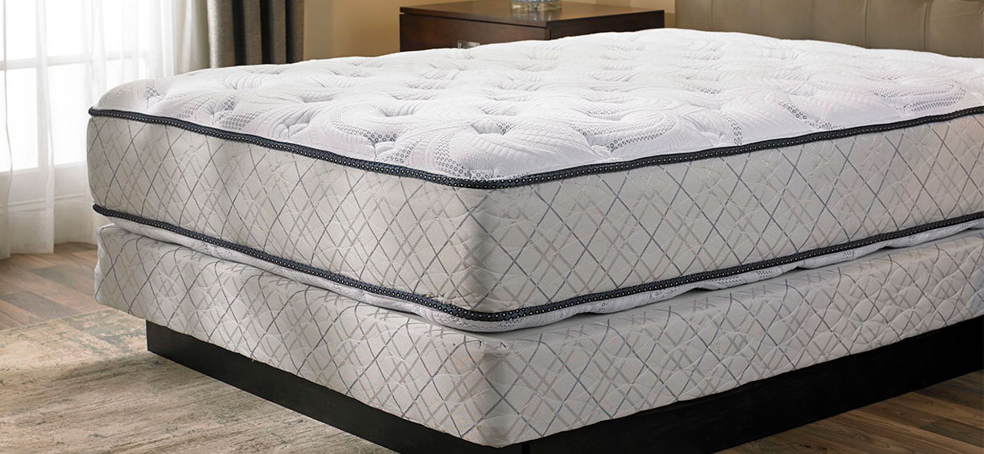 Box spring bed with mattress in the room.